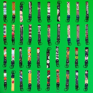 May include: A collection of 20 horror movie themed keychains. Each keychain features a different character or movie title. The keychains are black with a silver ring and a variety of colorful designs.