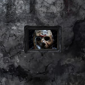 May include: A black and white photo of a hockey mask with red splatters of paint. The mask is in a black frame and is hanging on a cracked, gray wall.