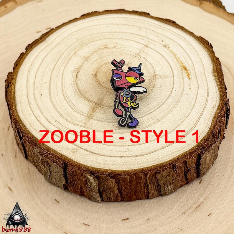 Puede incluir: Un colorido pin Zooble-Style 1, con un dise&ntilde;o de robot de dibujos animados con una cabeza rosa, un ojo amarillo y un sombrero peque&ntilde;o. El pin tiene un contorno negro y est&aacute; sobre un fondo de madera. El texto "ZOOBLE - STYLE 1" se muestra en rojo.