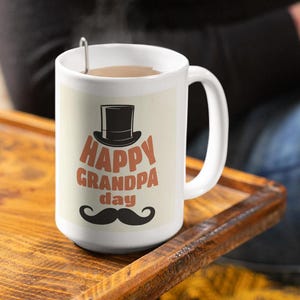 May include: White ceramic coffee mug with a brown and black top hat graphic and the text "Happy Grandpa Day" in orange and black lettering. A black mustache is below the text.