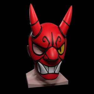 May include: A red Oni mask with black detailing and two horns. The mask has a fierce expression with a yellow eye, white teeth, and intricate design. The mask is displayed on a neutral-coloured stand against a black backdrop.