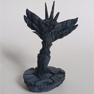 May include: A dark grey, 3D printed sculpture of a stylised tree with a bird-like form. The tree has a rough, textured surface and a base made of stone.