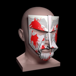 May include: A white mask with red paint splatters, covering the face of a mannequin. The mask has a geometric design and a pointed chin.
