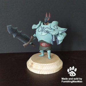 May include: A hand-painted figurine of a warrior with a wolf head, wearing blue armor with a snake design, holding a sword and standing on a wooden base. The base has a paw print logo and the text "Made and sold by FumblingMaoMao".
