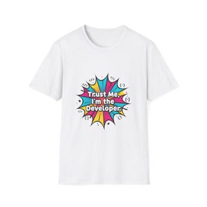 May include: White t-shirt featuring the text "Trust Me, I'm the Developer" in a colourful speech bubble design. The bubble has teal, yellow, pink, and blue accents, and code symbols.