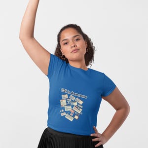 Könnte beinhalten: Ein königsblaues Kurzarm-T-Shirt mit dem Text "CSS Is Awesome", der über einer grafischen Collage aus verschiedenen rechteckigen Web-Layout-Elementen wie Rastern, Eingabefeldern und Navigationsleisten in gedeckten Beige- und Rottönen gedruckt ist.