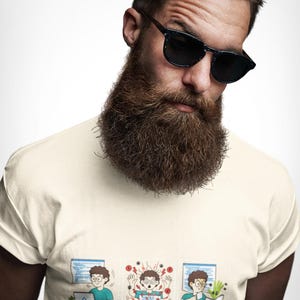 Puede incluir: Una camiseta de color crema con un gráfico de dibujos animados de tres paneles de una persona trabajando en una computadora. El texto debajo del gráfico dice: I Write Code. I Break Code. I Fix Code. El diseño representa el proceso de codificación.