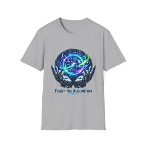 Può includere: T-shirt grigia con una grafica di una sfera luminosa tenuta da mani robotiche. La sfera mostra simboli matematici e il testo "Trust the Algorithm" in blu.
