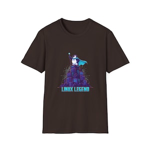 May include: A brown t-shirt with a cartoon penguin superhero wearing a blue cape and holding a staff, standing on a purple structure. The text "LINUX LEGEND" is displayed in teal below the image.