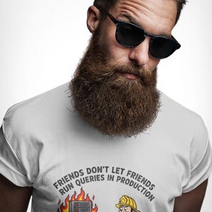 Può includere: Una t-shirt bianca con una stampa grafica che riporta il testo "FRIENDS DON'T LET FRIENDS RUN QUERIES IN PRODUCTION" sopra l'illustrazione di un vigile del fuoco che indica un server in fiamme mentre una persona usa una tastiera.