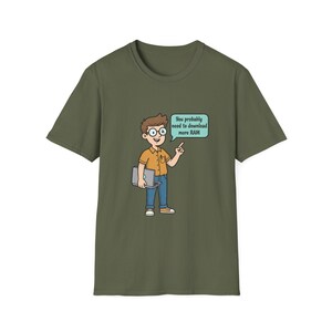 May include: Khaki green t-shirt with a cartoon graphic of a person holding a laptop and wearing glasses. The character is pointing to a speech bubble that says, "You probably need to download more RAM."