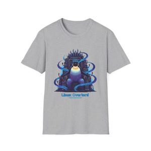 Op de afbeelding: Grijs t-shirt met een cartoonpinguïn op een troon. De pinguïn is in blauw en paars, met een kroon en blauwe energie. De tekst "Linux Overlord" staat eronder. Een ontwerp voor computerliefhebbers.