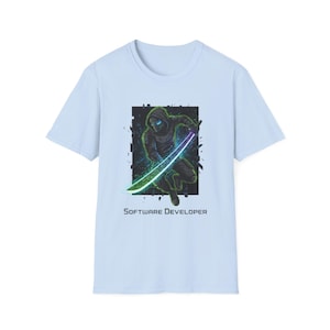 May include: Light blue t-shirt featuring a graphic of a ninja-like figure with a glowing sword. The figure is set against a dark, textured background. The text "SOFTWARE DEVELOPER" is printed below the graphic.