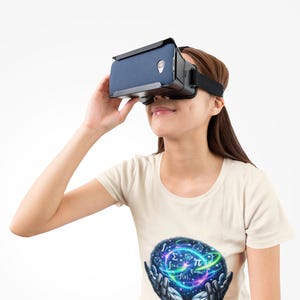 May include: A beige t-shirt featuring a graphic of robotic hands holding a glowing sphere filled with mathematical symbols and the text "TRUST THE ALGORITHM" in blue, worn with a black virtual reality headset with a blue fabric front panel.