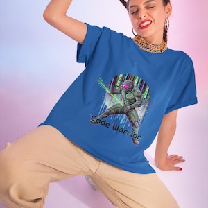 Puede incluir: Una camiseta de manga corta en color azul real con un estampado gráfico de una figura futurista con armadura en posición de combate. El diseño incluye un fondo circular con líneas digitales verticales y el texto Code Warrior.
