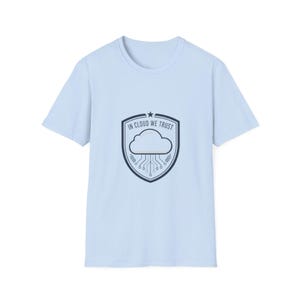 May include: Pale blue t-shirt with a round neck. The front displays a shield graphic with a cloud and circuit board design, and the text "IN CLOUD WE TRUST" in white. The design is centrally placed on the shirt.