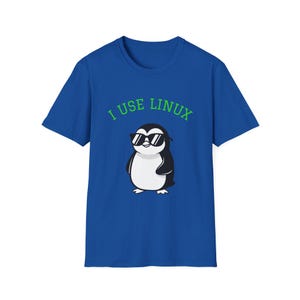 May include: Royal blue t-shirt with a cartoon penguin wearing sunglasses. The penguin is black, white, and grey. The text "I USE LINUX" is printed above the penguin in green letters.