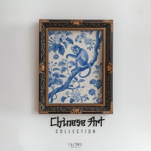 Peut inclure: Une estampe encadrée d'un style chinois bleu et blanc représentant un singe assis sur une branche d'un arbre fleuri. Le cadre est noir avec des accents dorés. Le texte "Chinese Art Collection" est sous l'image.