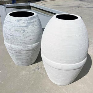 Pode incluir: Dois vasos de cer&acirc;mica branca com acabamento texturizado. O vaso &agrave; esquerda tem um lavado cinza claro, enquanto o vaso &agrave; direita &eacute; branco s&oacute;lido.
