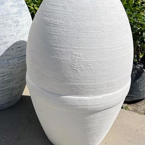 Pode incluir: Dois vasos de cer&acirc;mica branca com acabamento texturizado. O vaso maior &eacute; mais alto e mais largo que o menor.
