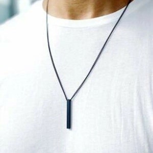 Peut inclure: Un collier à chaîne noire avec un pendentif en forme de barre noire long et fin.
