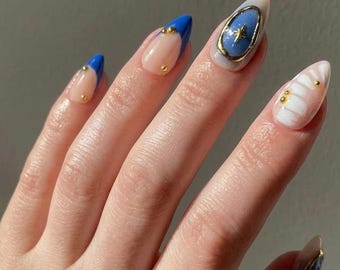 Uñas postizas azules con punta francesa, forma almendrada, estrellas doradas y detalles de mármol – Hechas a mano