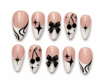 Uñas postizas con punta francesa y lazo de cereza negra – Uñas almendradas rosa nude con diseño de estrella, dije de cereza con lazo 3D / Set de uñas minimalista de lujo