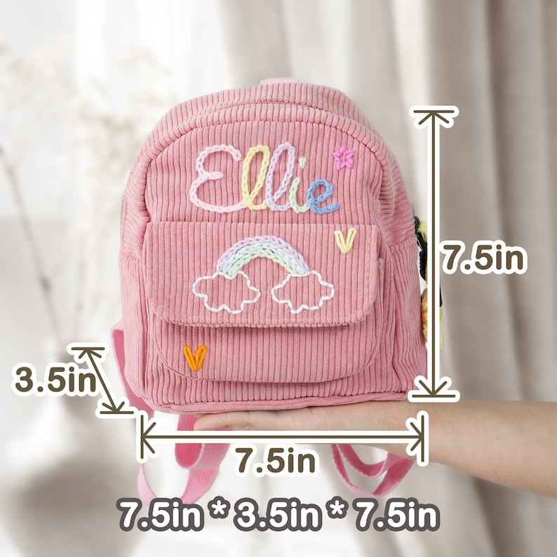 May include: Pink corduroy mini backpack with a rainbow and cloud embroidery and the name "Ellie" embroidered on the front. The backpack measures 7.5 inches tall, 7.5 inches wide, and 3.5 inches deep.