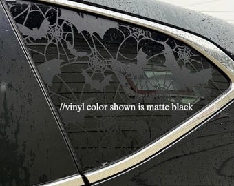 Może przedstawiać: Matowa czarna naklejka winylowa na szybie samochodu z powtarzającym się wzorem pajęczyn i sylwetek latających nietoperzy. Tekst //vinyl color shown is matte black jest nadrukowany na biało na środku szyby.