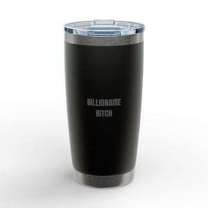 Puede incluir: Un vaso de acero inoxidable negro mate con tapa de plástico transparente. La parte frontal del vaso presenta el texto BILLIONAIRE BITCH grabado en una fuente sans-serif clara. La base y el borde superior tienen un acabado plateado metálico.