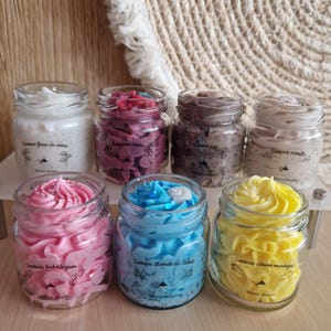 Peut inclure: Collection de sept pots en verre remplis de cire parfumée colorée. Les pots sont étiquetés en français et présentent diverses couleurs, dont le blanc, le rose, le bleu et le jaune. La cire est tourbillonnée et texturée, ressemblant à du glaçage.