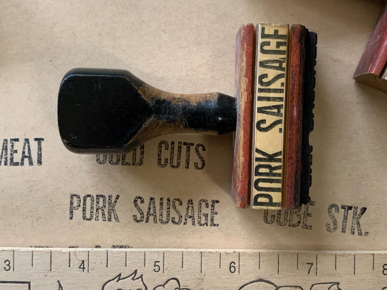 Puede incluir: Un sello de madera con un marco rojo y blanco y el texto "PORK SAUSAGE" en letras negras. El sello se utiliza para marcar productos c&aacute;rnicos.