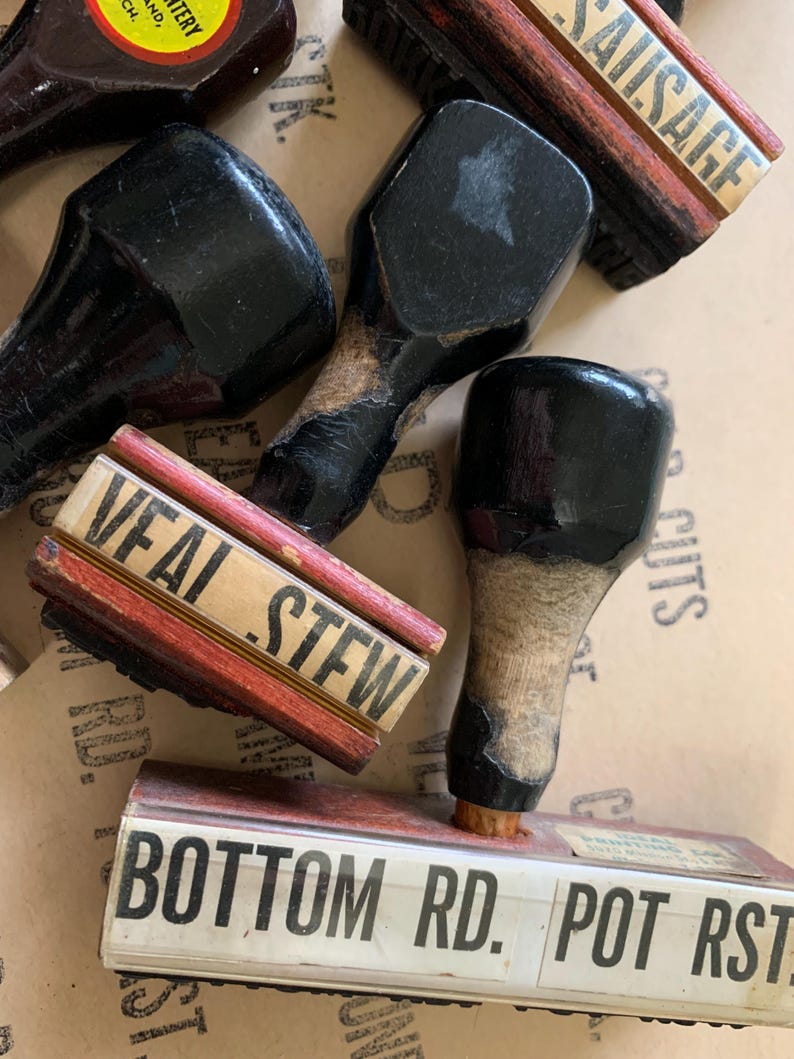 Puede incluir: Cuatro sellos de goma vintage de madera con almohadillas de tinta negra. Los sellos dicen "SAUSAGE", "VEAL STEW", "BOTTOM RD." y "POT RST."