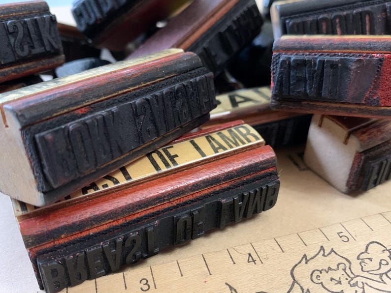 Puede incluir: Una colecci&oacute;n de sellos de goma de madera vintage con varias frases, incluyendo "HOWEVER", "BEST OF I AM" y "PREVAL OF WAR". Los sellos est&aacute;n dispuestos en una pila sobre una superficie marr&oacute;n.