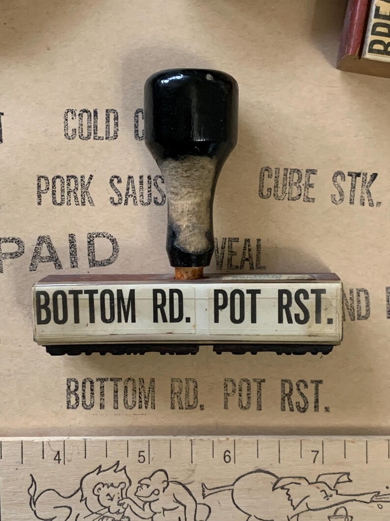 Puede incluir: Un sello de madera con un mango negro y una superficie rectangular blanca. El sello dice "BOTTOM RD. POT RST."