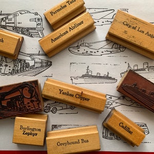 May include: A collection of wooden stamps featuring various modes of transport, including a train, aeroplane, bus, and boat. The stamps are labelled with names such as "Queen Elizabeth", "American Airliner", "City of Los Angeles", "Yankee Clipper", "Burlington Zephyr", "Greyhound Bus", "Parmelee Taxi", and "Cadillac".