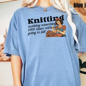 May include: A blue jean t-shirt with the text "Knitting: stabbing something 1,000 times without going to jail" and a retro illustration of a woman knitting.