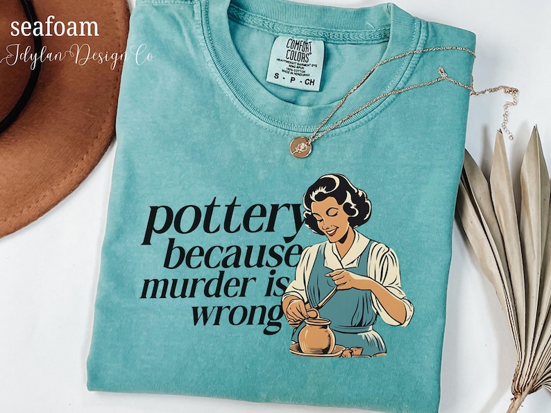 May include: A teal blue t-shirt with the text "pottery because murder is wrong" and a cartoon image of a woman making pottery.