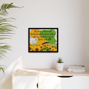 Puede incluir: Impresión enmarcada con un marco negro, que representa un campo de girasoles bajo un cielo nublado. La obra de arte incluye el texto "El Señor está cerca de los quebrantados de corazón, y salva a los de espíritu abatido. Salmo 34:18 (NIV)".