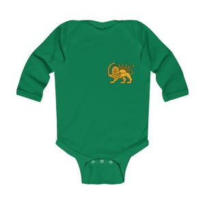 Op de afbeelding: Een groene babybody met lange mouwen met een gouden embleem van een leeuw die een zwaard en een zon vasthoudt. De body heeft een ronde halslijn en drie drukkers aan de onderkant.