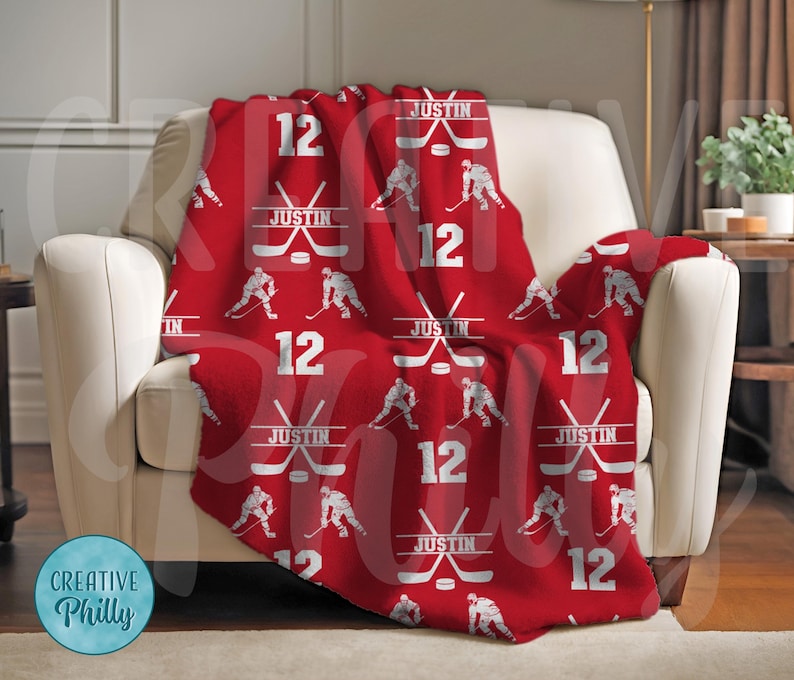 May include: Red fleece blanket with a hockey player and stick pattern. The blanket features the name "Justin" and the number "12" repeated throughout.