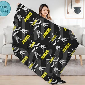 May include: Black and white hockey player pattern fleece throw blanket with the name "Jones" and the word "Lions" repeated throughout the design.