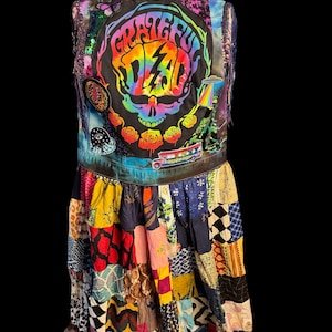 Könnte beinhalten: Eine ärmellose Jeansweste mit einem großen Grateful Dead Totenkopf-Motiv, Aufnähern und Fransen, befestigt an einem mehrfarbigen Patchwork-Rock. Die Weste zeigt einen Batik-Totenkopf, Rosen, einen Bus und einen Aufnäher mit einem Auge.