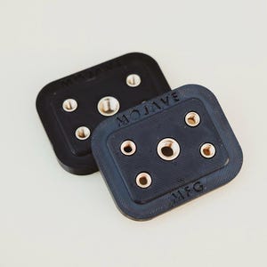 Puede incluir: Dos placas de plástico negro con varios agujeros y el texto "MOJAVE MFG" en una de las placas.