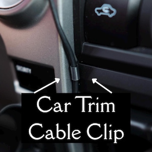 May include: A close-up of a car's interior, showcasing a black cable secured by a silver clip. The text "Car Trim Cable Clip" is displayed on a black background, indicating the product's function and type.