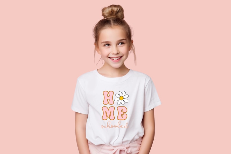 K&ouml;nnte beinhalten: Ein wei&szlig;es T-Shirt mit einer pinkfarbenen und orangenen Grafik, auf der "HOME" mit einer G&auml;nsebl&uuml;mchen im "O" und "schooled" darunter steht.