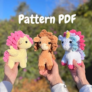 May include: A crochet pattern PDF for making three amigurumi toys: a unicorn, a lion, and a pegasus. The unicorn is white with a pink mane and tail, the lion is brown with a brown mane, and the pegasus is yellow with a pink mane and wings.
