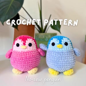 Puede incluir: Dos juguetes de pingüino de ganchillo, uno rosa y otro azul, con pies y picos amarillos. El texto "CROCHET PATTERN" y "No-sew penguin" se muestran en la imagen. Los pingüinos están sobre una superficie blanca.