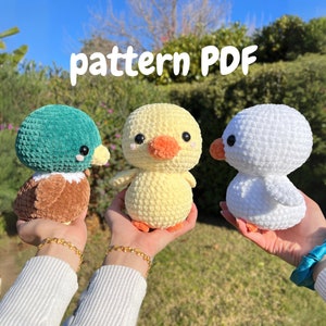 Puede incluir: Tres animales de peluche tejidos a crochet: un patito con hilo amarillo, un pato con hilo verde y marrón, y un pollito blanco. Los animales están en las manos de dos personas. El texto "pattern PDF" está escrito en letras blancas sobre un fondo verde.