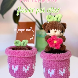 Puede incluir: Dos nutrias de maceta de ganchillo. Una maceta tiene un brote de hoja verde, la otra tiene una nutria marrón sosteniendo una flor rosa. Las macetas son rosas con diseños de corazón blanco. El texto dice "PATTERN PDF" y "Flower pot otter".